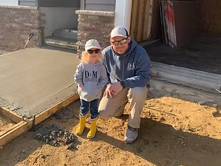 Grandfather and grandson on a freshly poured slab in D&M Concrete gear